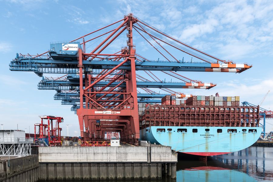 Gantry cranes working containers on a vessel alongside a terminal berth