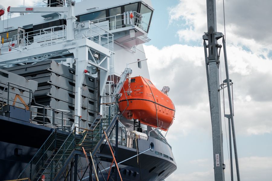 Orange freefall lifeboat stowed on its davit aboard a vessel